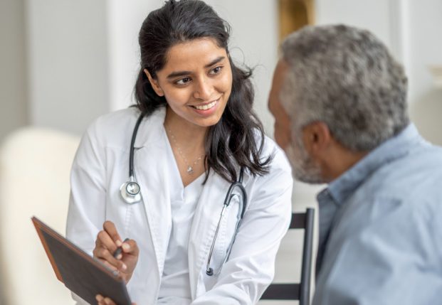 Doctor sitting with patient holding a clipboard while smiling