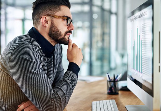 Business worker review charts on a screen while sitting at desk in the office.