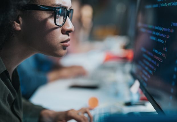 Female coder working on computer screen with code on it.