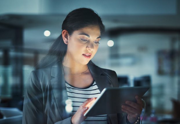 Woman with suit jacket reviewing information on a tablet.