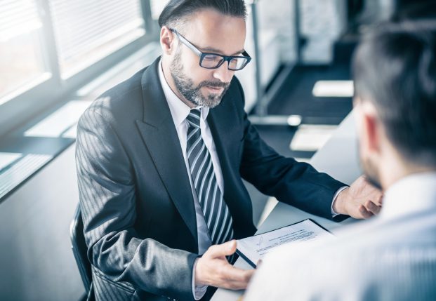 Business man in suit working with client reviewing documents together.